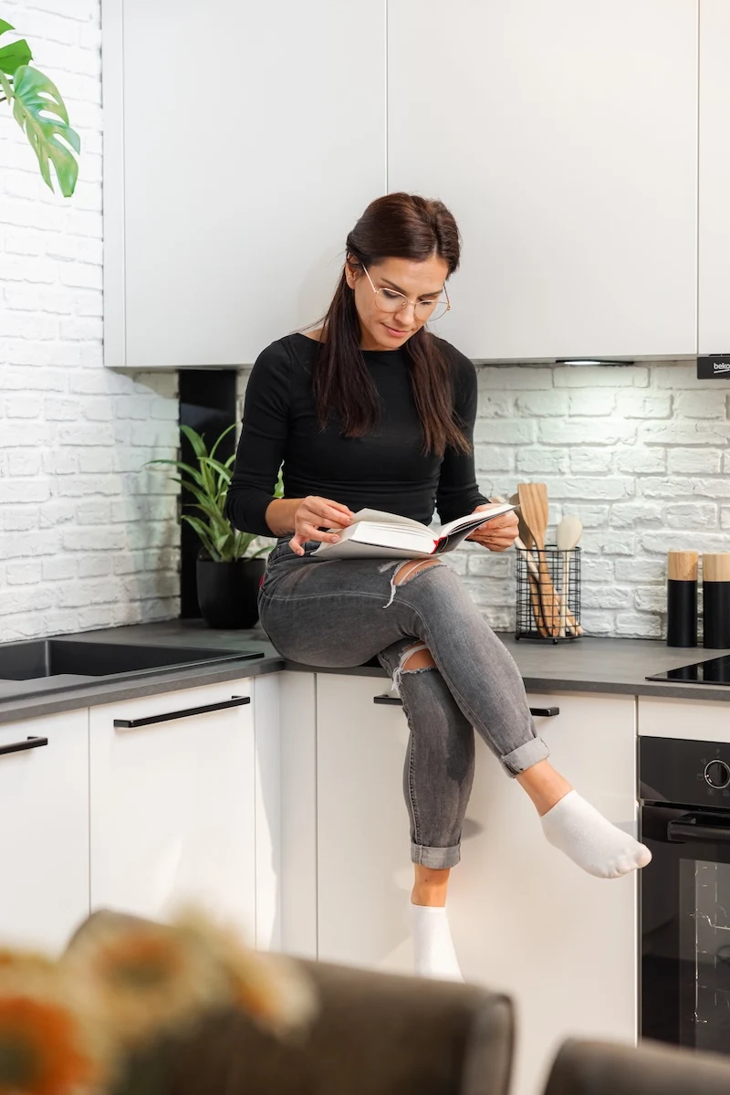 Frau sitzt auf der neuen Cozy Chic L - Küche von DAN FIRST